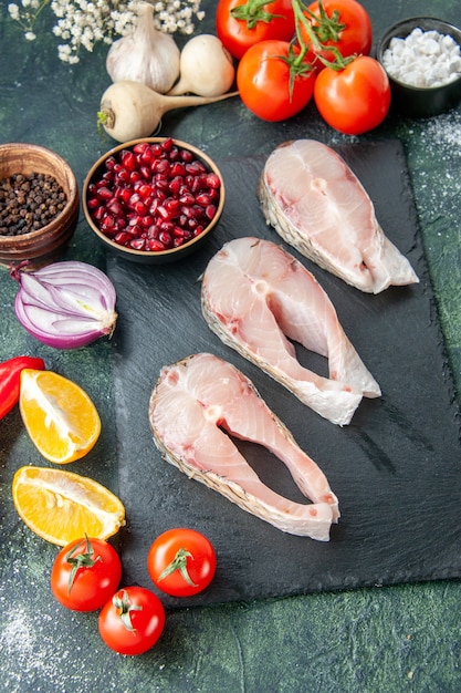 Vue de dessus des tranches de poisson frais avec des tomates rouges sur la table sombre fruits de mer océan viande repas de mer plat de poivre nourriture salade eau