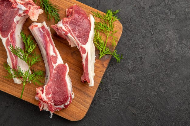 Vue de dessus des tranches de viande crue avec des verts sur fond sombre couleur de vache photo de viande animal poivre poulet cru espace libre