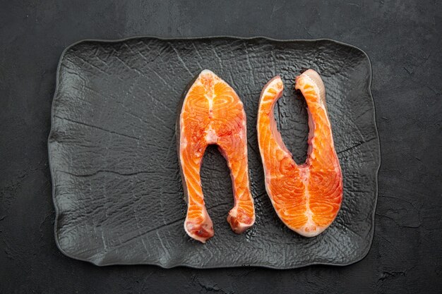 Vue de dessus des tranches de viande fraîche à l'intérieur de la plaque sur fond sombre