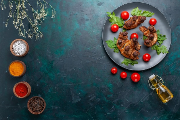 Vue de dessus des tranches de viande frite avec de l'huile d'olive et des assaisonnements sur le bureau bleu foncé repas santé viande végétale