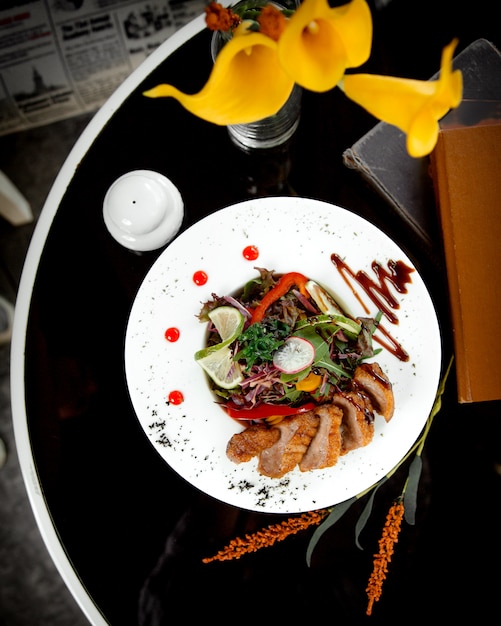 Vue de dessus de tranches de viande frites croustillantes servies avec une salade de légumes