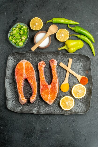 Vue de dessus des tranches de viande frites avec des poivrons et du citron sur fond sombre