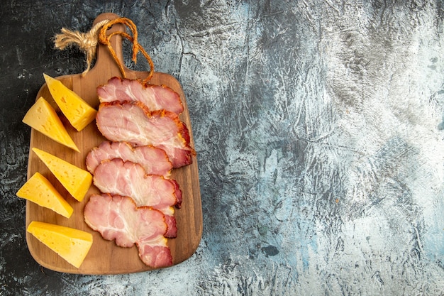 Vue de dessus des tranches de viande tranches de fromage sur une planche à découper sur fond gris