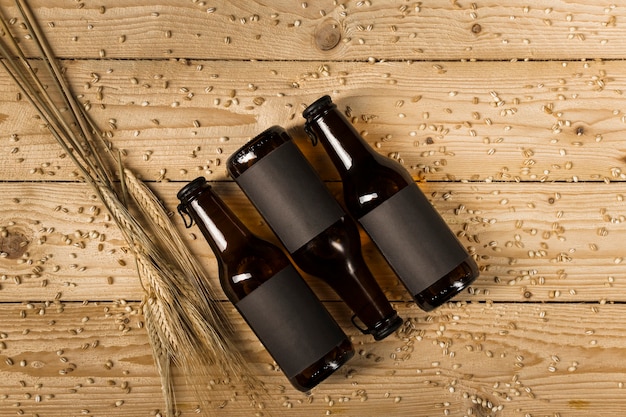 Vue de dessus de trois bouteilles de bière et d&#39;épis de blé sur une planche en bois