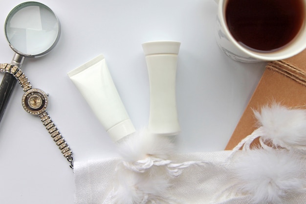 Photo gratuite vue de dessus d'un tube de crème avec montre lotionnd avec une loupe et une tasse de thé sur la table