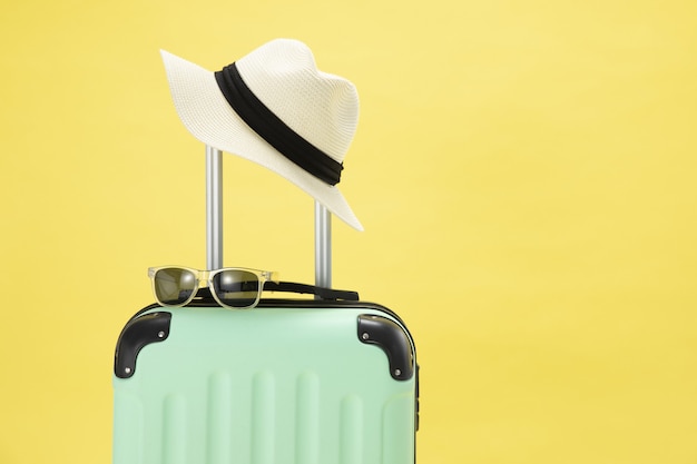 Vue de dessus d'une valise, lunettes de soleil, appareil photo et chapeau sur fond jaune - concept de vacances