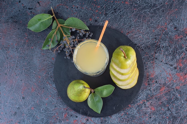 Vue de dessus. Verre de jus de poire avec des poires tranchées vertes sur planche de bois