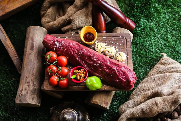 Vue de dessus de la viande crue aux tomates champignons avec fromage poivron et épices sur un plateau