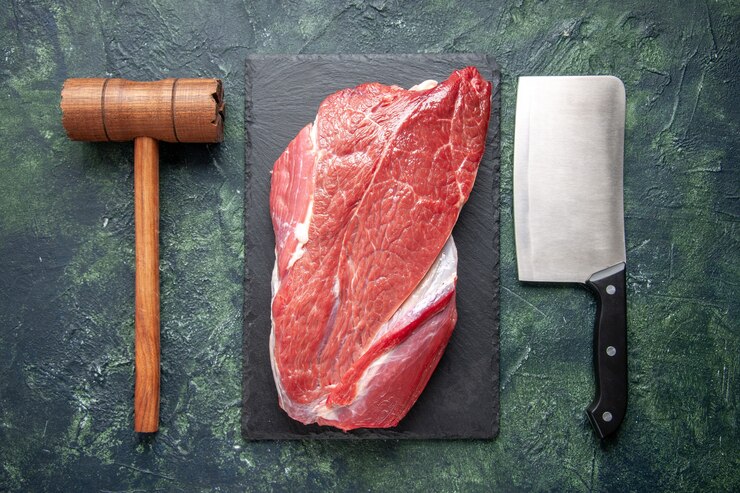 Photo gratuit vue de dessus de la viande crue rouge fraîche sur une planche à découper un marteau et une hache en bois sur fond de couleur vert noir mélangé
