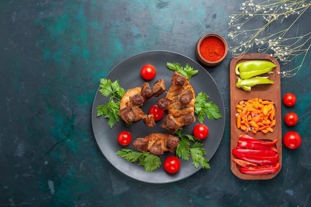 Vue de dessus de la viande cuite en tranches avec des verts et des tomates cerises à l'intérieur de la plaque sur le fond bleu