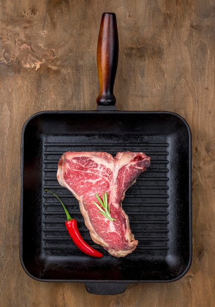 Vue de dessus de la viande dans la poêle avec du piment et des herbes