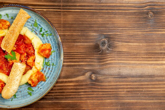 Vue de dessus de la viande en sauce avec purée de pommes de terre et pain tranché sur une table en bois marron