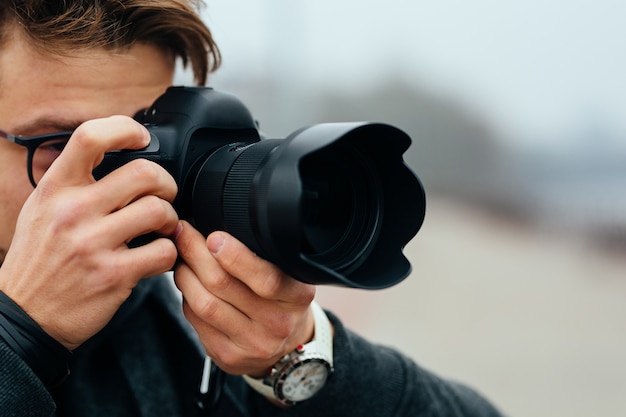 Photo gratuite vue de détail du jeune homme à lunettes prenant des photos dans la rue.