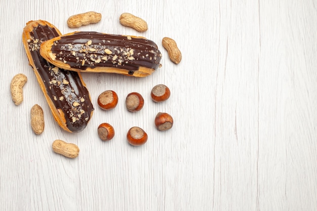 Vue du côté supérieur gauche éclairs au chocolat et noisettes et arachides éparpillées sur la table en bois blanc