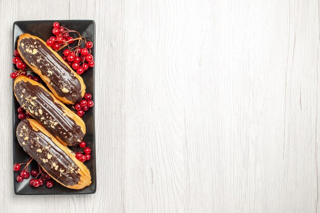 Vue Du Haut à Gauche éclairs Au Chocolat Et Groseilles Sur La Plaque Rectangulaire Noire Sur Le Sol En Bois Blanc