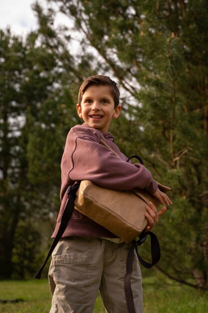 Photo gratuite vue du petit garçon avec sac à dos explorant la nature