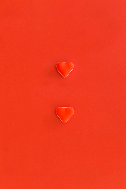 Vue élevée de deux bonbons en forme de coeur sur fond rouge