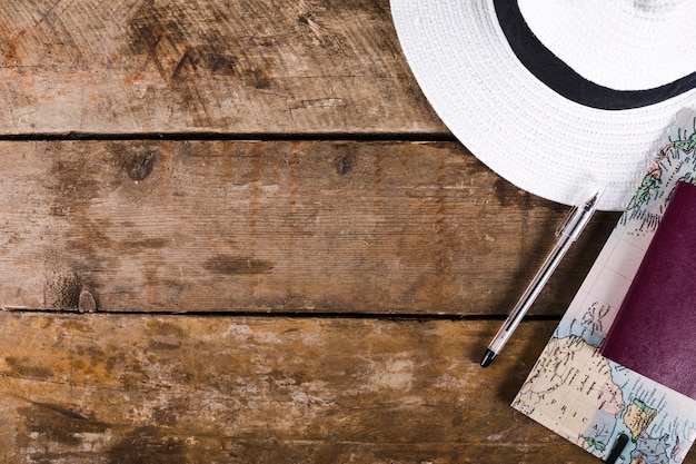 Vue élevée du chapeau, carte, passeport et stylo sur la surface en bois