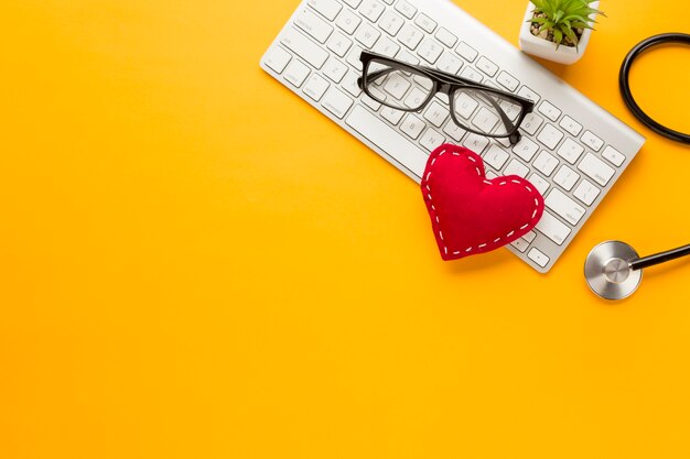 Vue élevée du clavier sans fil; lunettes; plante succulente; avec jouet en tissu cousu sur fond jaune