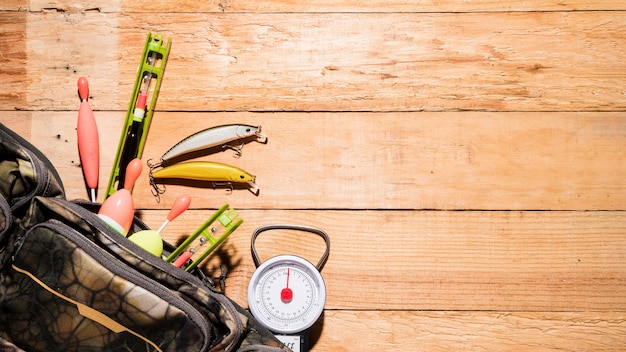 Photo gratuite une vue élevée du flotteur de pêche; leurre et balance sur un bureau en bois