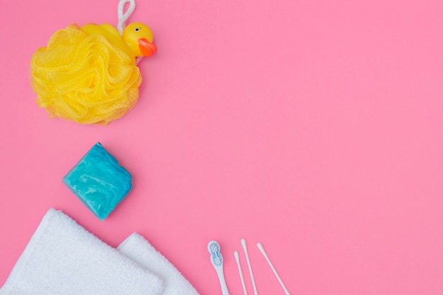 Photo gratuite vue élevée de l'éponge de bain; savon; coton-tige et serviette sur fond rose