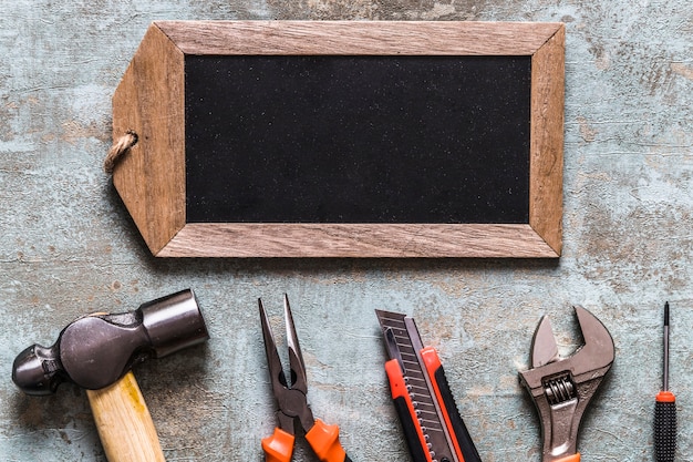 Photo gratuite vue élevée de l'étiquette en bois blanc et divers outils de travail sur le vieux fond en bois