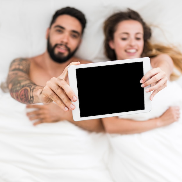 Vue élevée, de, jeune couple, coucher lit, tenue, tablette numérique