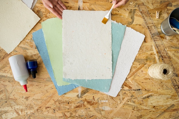 Photo gratuite vue élevée de la main d'une femme à l'aide d'un pinceau sur des papiers faits à la main