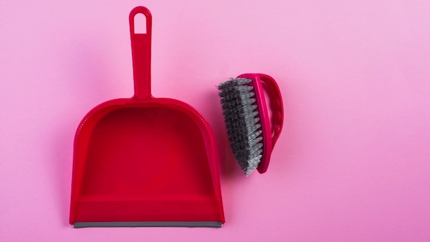 Vue élevée de la poubelle rouge et brosse sur fond rose