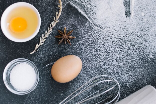 Vue élevée de sucre; Oeuf; céréales; anis étoilé; fouetter et fariner sur le comptoir de la cuisine