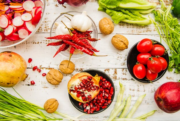 Vue élevée de tomate cerise; piments rouges; oignon de printemps; Ail; feuilles de bette à carde; persil; grenade mûre et noix