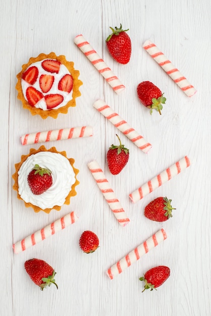 Vue éloignée du haut de petits gâteaux crémeux avec des fraises fraîches et des bonbons sur la lumière, gâteau aux fruits sucrés berry bake