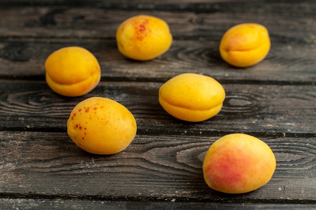 Vue de face abricots jaunes frutis moelleux et frais sur le fond rustique brun