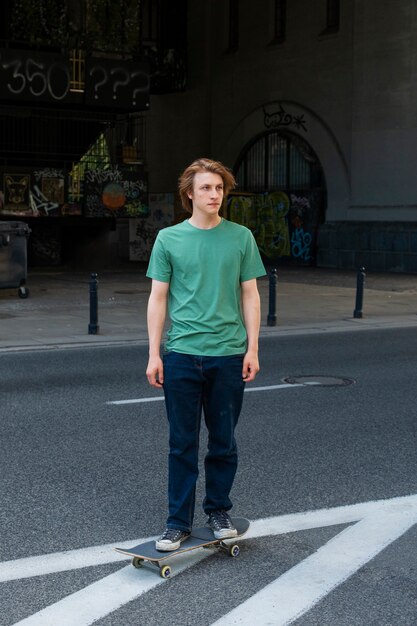 Vue de face adolescent debout sur une planche à roulettes