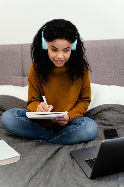 Vue de face d'une adolescente à l'aide d'un ordinateur portable pour l'école en ligne