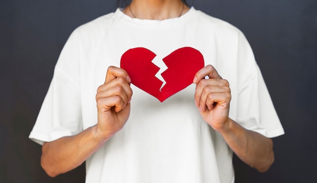 Vue de face adulte tenant un coeur brisé rouge