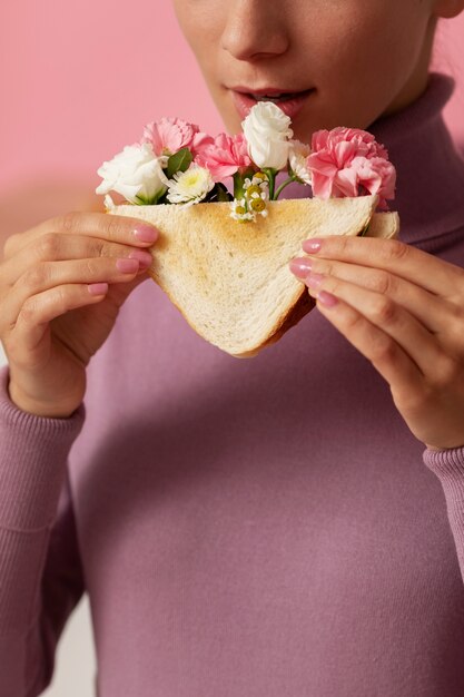 Vue de face adulte tenant un sandwich avec des fleurs