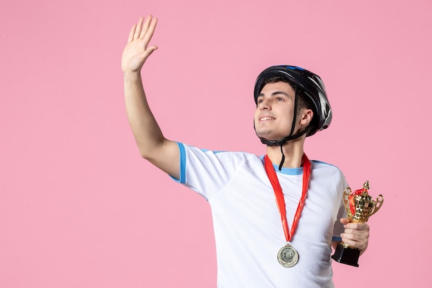 Vue de face en agitant un athlète masculin dans des vêtements de sport tenant une coupe d'or avec un casque