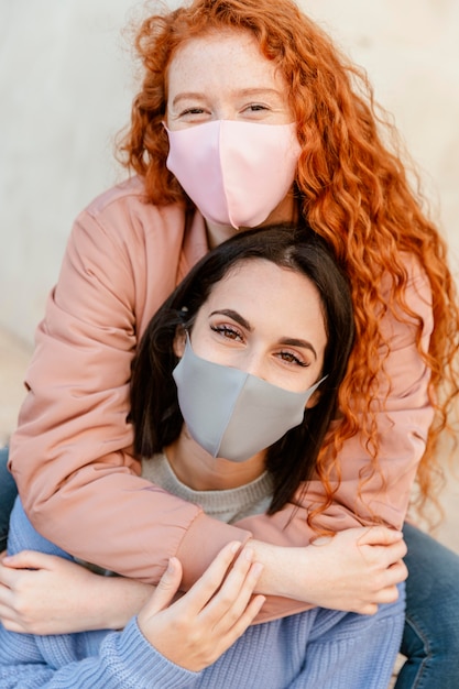 Vue de face des amies smiley avec des masques faciaux à l'extérieur