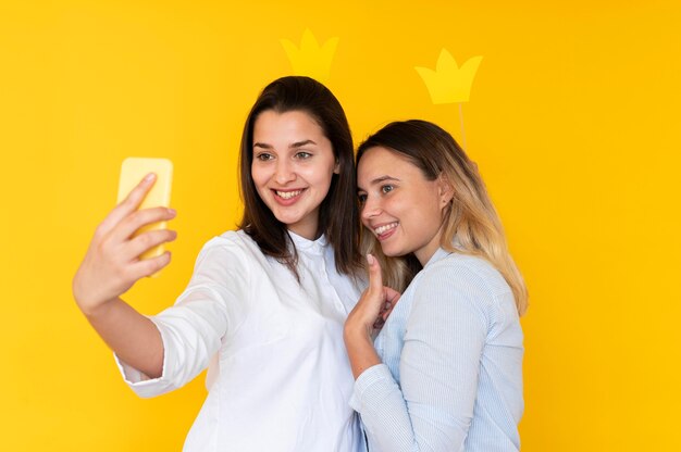 Vue de face d'amis prenant des selfies avec couronne