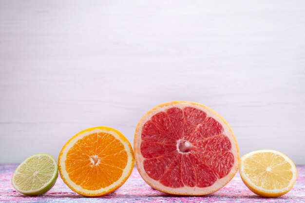 Vue de face des anneaux d'agrumes pamplemousses oranges limes sur le bureau léger