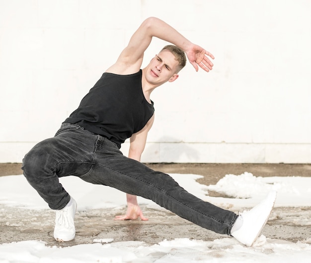 Vue de face de l'artiste hip hop dansant à l'extérieur avec de la neige