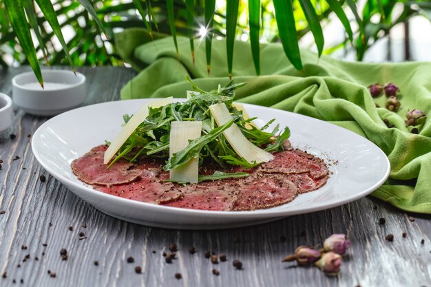 Vue de face assiette de viande basturma avec roquette et parmesan