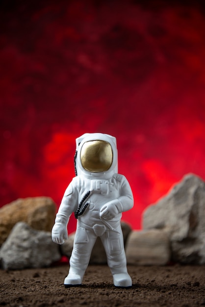 Vue de face de l'astronaute blanc avec des roches sur la surface rouge de la lune cosmique fantastique de science-fiction