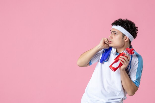 Vue de face de l'athlète masculin effrayé dans des vêtements de sport avec une bouteille d'eau