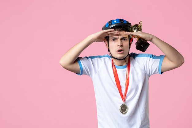 Vue de face de l'athlète masculin en vêtements de sport tenant une coupe d'or avec un casque