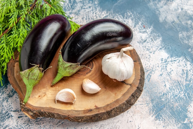 Vue de face aubergines ail sur planche de bois d'arbre sur fond bleu-blanc