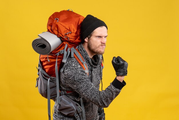 Vue de face de l'auto-stoppeur masculin en colère avec des gants en cuir et sac à dos étant prêt à se battre