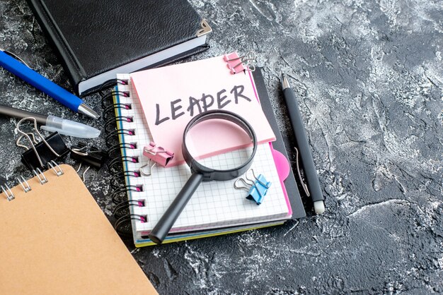 Vue de face autocollant rose avec stylo note écrite leader et cahiers sur surface grise emploi école de commerce bureau photo couleur