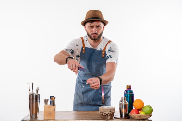 Vue de face barman masculin devant le bureau avec shakers et fruits sur le mur blanc job bar alcool club night boissons service